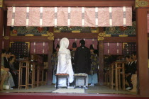 Nezu Jinja. Shinto priests give sake to bride and groom  both in traditional costume  as part of Shinto wedding ceremony