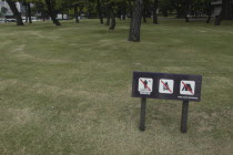 Sign on park grass between Hibiya and Nijubashi prohibiting walking on grass  fires  and camping. Aimed at homeless people