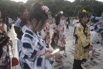 Harajuku. A member of Kyoto Rokumeikan troupe checks her mobile / cell phone during a break from dancing at Yoyogi Park dressed in half kimono costume on Saturday afternoonall junior high and senior...