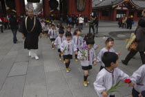 Asakusa. 4 year old nursery students from Senso-ji Dembo-in Nursery  carrying flowers to present to Buddha as part of his birthday celebrations  accopamied by Buddhist monk
