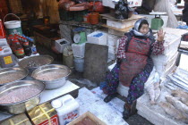 Namdaenum Market on a cold December day. Elderly woman negotiates price with a buyer for frozen or fermented fish