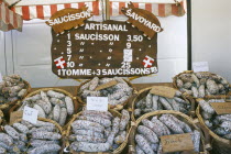 Samoens.  Baskets of different flavoured pork sausages for sale on market stall.
