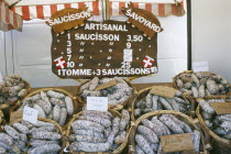 Samoens.  Baskets of different flavoured pork sausages for sale on market stall.