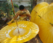 Man spinning cotton umbrella as he applies colour finnishColor