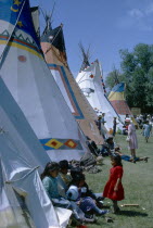 Colourful Native North American Indian Tepees with people gathered on grass.colorful
