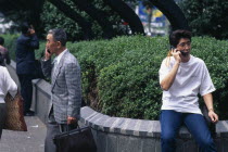 Three men ranging in age talking on mobile phones.