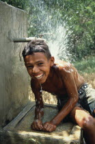 Boy cooling off under a standpipe.  Water