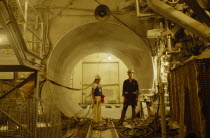 Interior of nuclear reactor plant with two male workers.