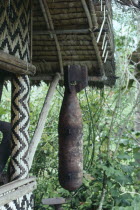 Cargo cult bomb found and been venerated and hanging outside a wooden house.