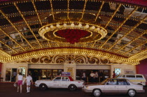 Brightly lit red and gold Hotel Casino with taxi cabs parked outside.