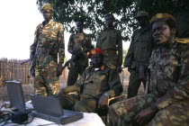 Commander Geia of the SPLA army sat down surrounded by soldiers with a lap top computer on the table in front of him.