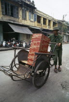 Man standing in the street with boxes of Coke in his cyclo.