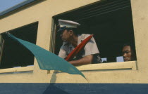 Guard on train to Ayuthaya leaning out of carriage window with signal flags.
