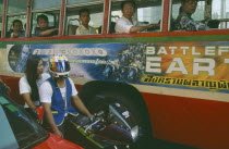 Motorcyclist in traffic jam next to bus with advertising for science fiction film on side depicting futuristic transport.congestion