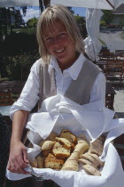 Smiling woman holding a basket of Swedish bread at Oaxen Skargards Krog restaurant