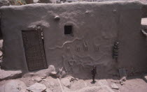 Detail of exterior wall and door of chiefs house with small child standing outside.