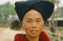 Yao tribeswoman wearing a tribal headdress with a hoe slung over her shoulder
