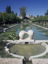 Alcazar de los Reyes Cristianos and its gardens with large pond and modern sculpture in the foregroundAndalusia Andalucia
