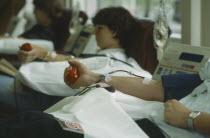 Men and women donors giving blood with mans arm in the foreground