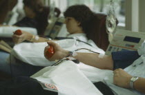 Men and women donors giving blood with mans arm in the foreground