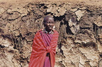 Maasai woman in front of mud and straw hut