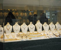Gold Souq.  Three women in black Burqa inside jewellery shop  seen through window with display  of gold and silver.