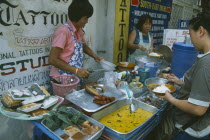 Women serving various curries from a pavement stall