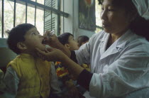Primary school children receiving oral polio immunization from nurse.