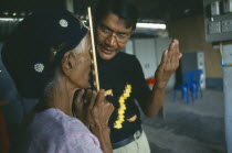 Male optician giving an elderly woman an eye test at the Mae Tao Clinic.