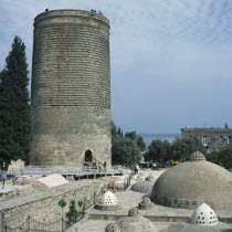 Maidens Tower.  Circular stone tower with visitors standing on the top and at the entrance below.