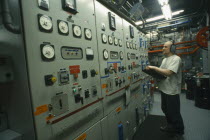 US Amundsen-Scott South Pole Station.  Man with clipboard at contol panels in the power plant.