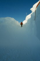 US Amundsen-Scott South Pole Station.  Figure walking through entrance way to the geodesic dome  high banks of drifted snow on either side.