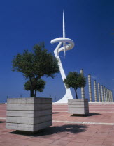 Olympic stadium.  The Torre Calatrava  trees planted in stone tubs on a paved area in the foreground.