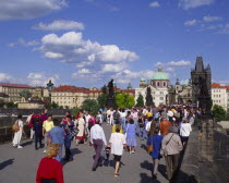Mala Strana.  Crowds of people crossing Charles Bridge.  Typical houses in the background.