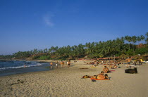 India, Goa, Little Vagator beach, view along beach  people sunbathing and beach bar on right.