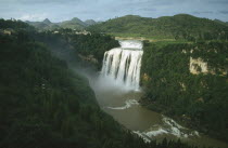 Huangguoshu Falls seen from a distance within lush green surrounding landscape
