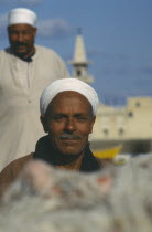 Two men wearing white turbans in front of mosque