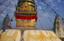 Swayambhunath Temple.  Detail of roof dome with painted face hung with prayer flags.