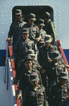 Soldiers descending steps of a plane after returning from Angola