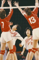 Players leaping for ball at net in Norway versus Japan match.