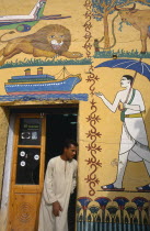 Man at door of tourist shop decorated with mock hieroglyphics depicting the 20th CenturyAeroplane  Ship  Man with umbrella  lion