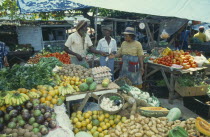 Two women buying fruit from vendor in market