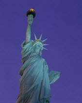 Angled view looking up at the Statue of Liberty at night