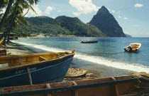 Stretch of sandy beach with boats moored in the foreground and the Pitons beyond.Windward IslandsWindward Islands