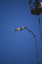 Man diving from a crane with elastic cord tied to his ankles