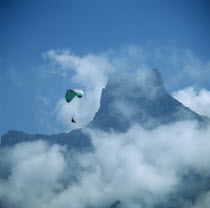 View of mountain top through mist with paraglider