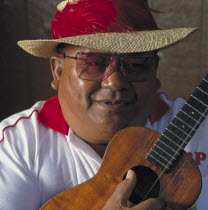 Man wearing straw hat playing a ukulele