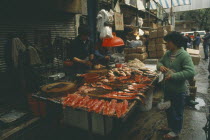 Fish stall in the market with vendor and customer.