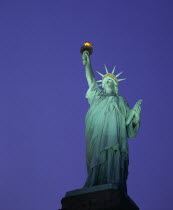 Angled view looking up at the Statue of Liberty at night