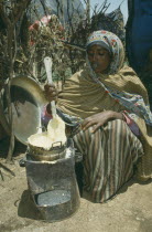 Ethnic Somali woman cooking porridge over fuel saving stove.Intermediate technology